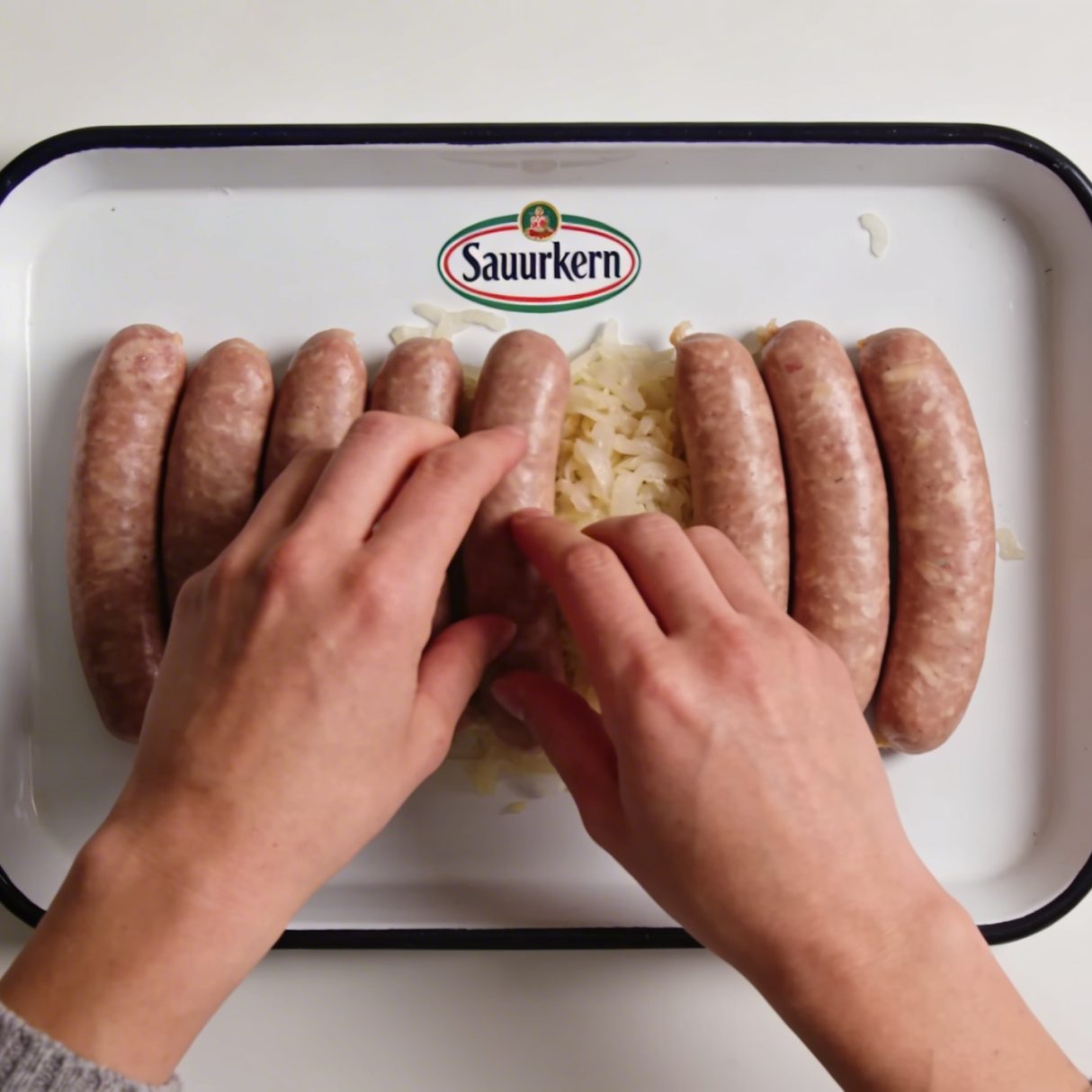 Assiette de choucroute crue marquee, mains dressant saucisses