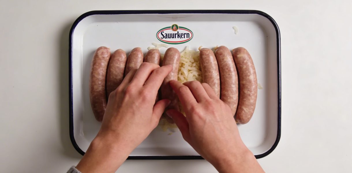 Assiette de choucroute crue marquee, mains dressant saucisses