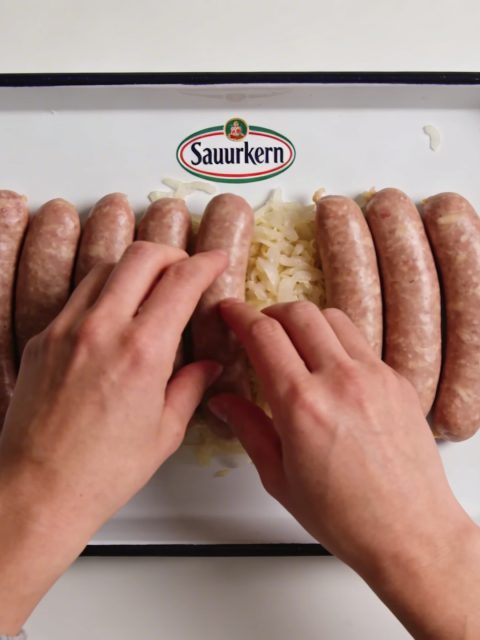 Assiette de choucroute crue marquee, mains dressant saucisses