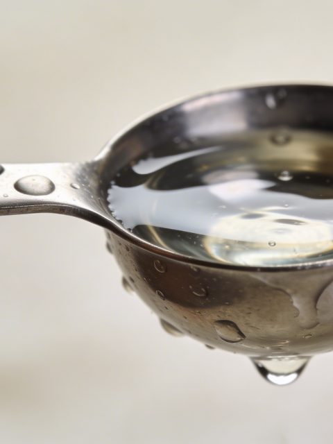 Cuillere doseuse en metal remplie d eau