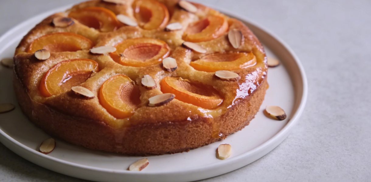 gros gateau dore aux abricots tranches et amandes sur assiette blanche