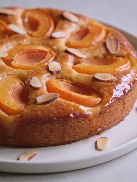 gros gateau dore aux abricots tranches et amandes sur assiette blanche