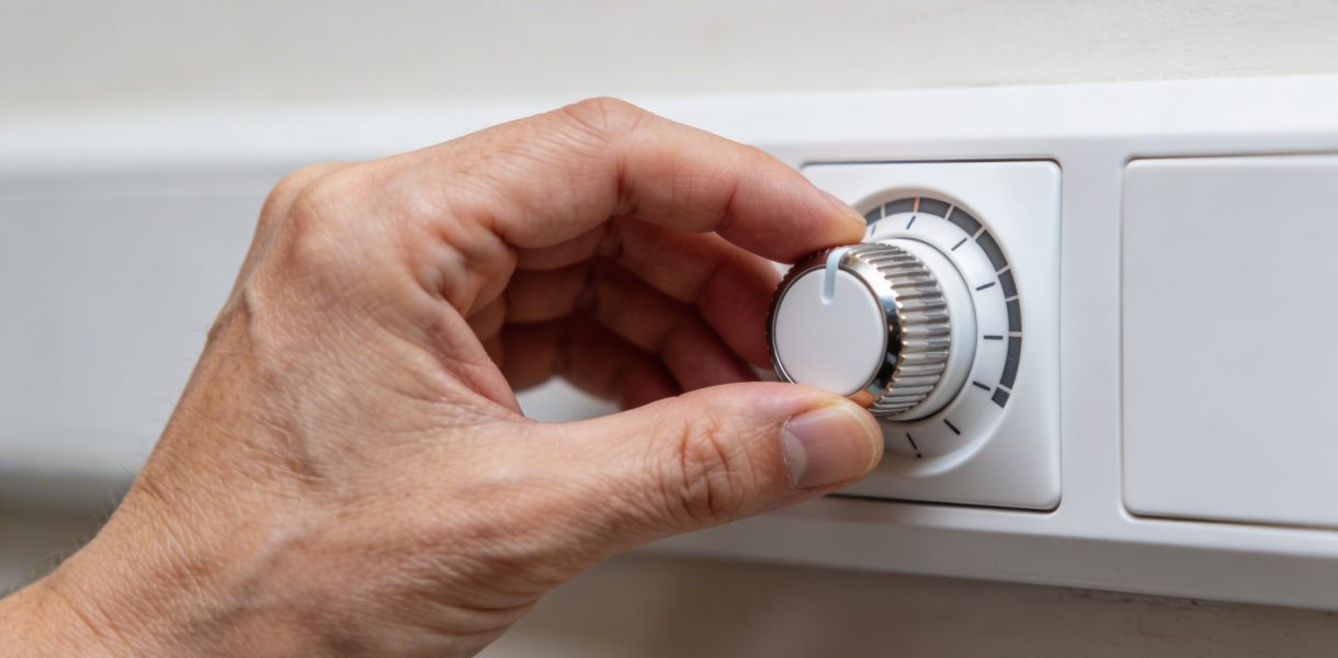 Gros plan sur main ajustant molette de thermostat