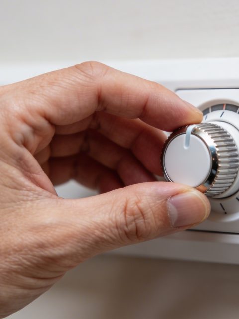 Gros plan sur main ajustant molette de thermostat