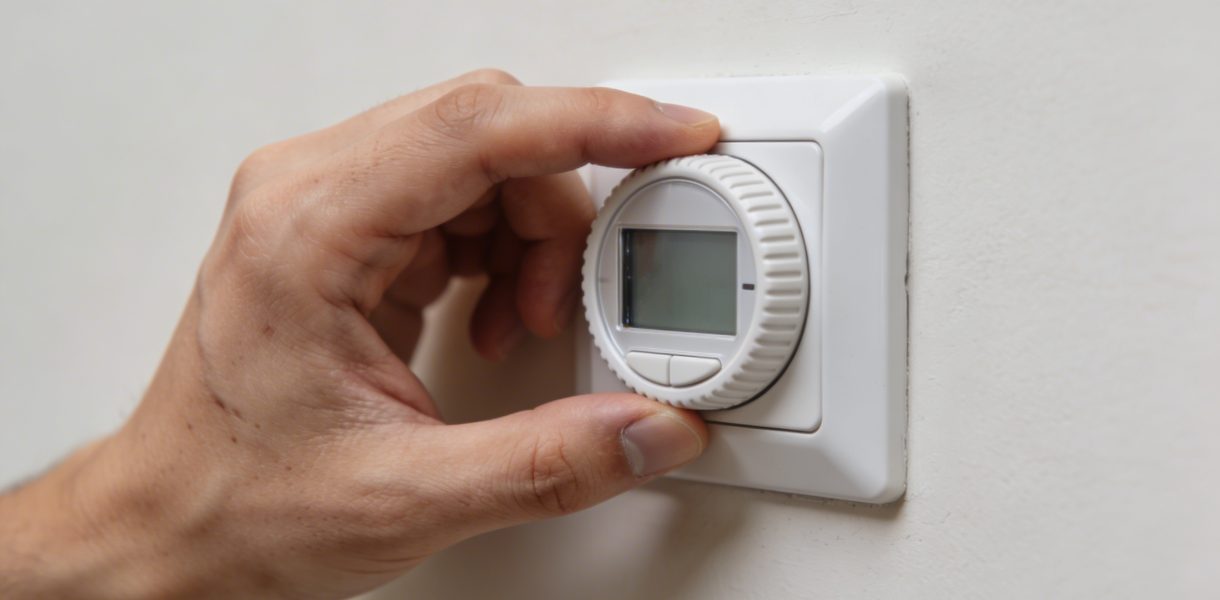 Gros plan main ajustant thermostat mural sur 7
