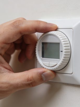 Gros plan main ajustant thermostat mural sur 7
