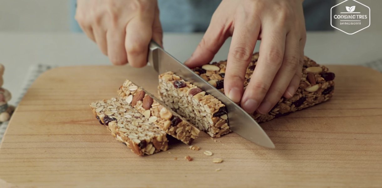 mains coupant des barres de cereales maison
