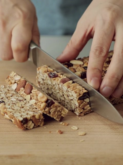 mains coupant des barres de cereales maison
