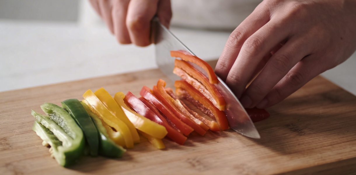 Mains coupant des legumes en fines lamelles colorées