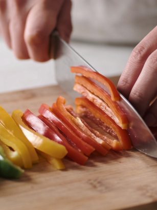 Mains coupant des legumes en fines lamelles colorées