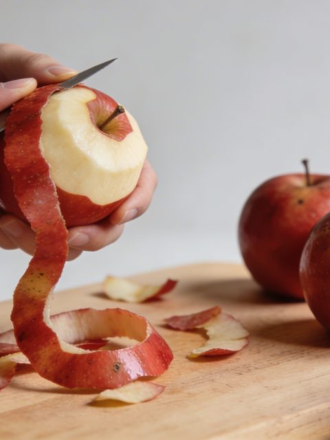 Mains epluchant des pommes rouges sur planche