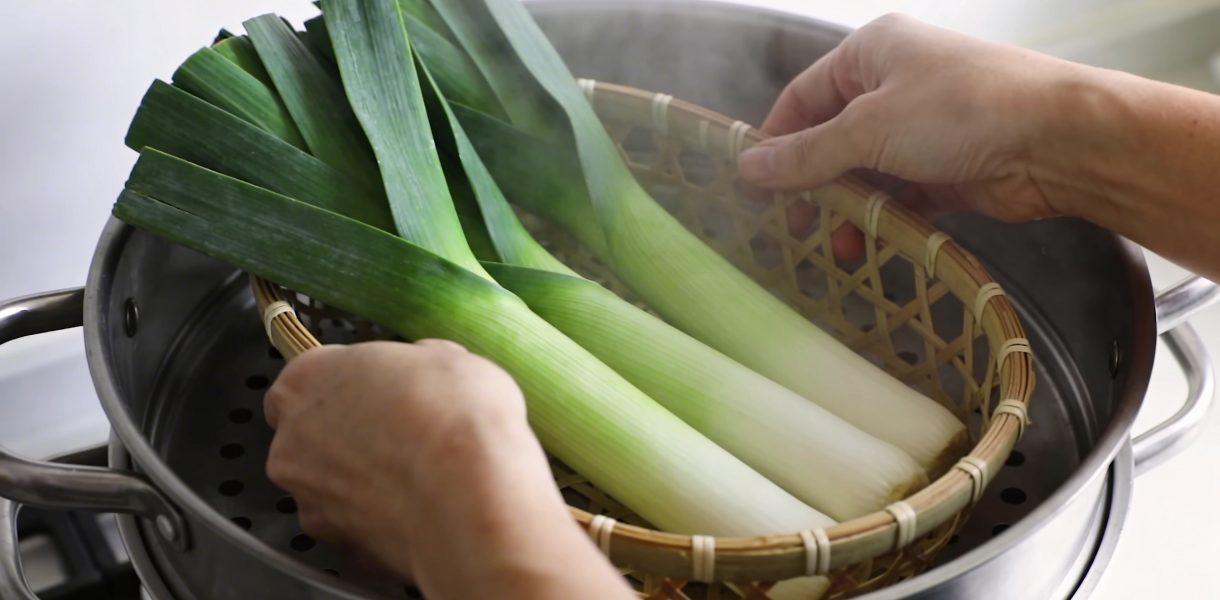 Mains ajustant panier de poireaux verts dans cuit vapeur