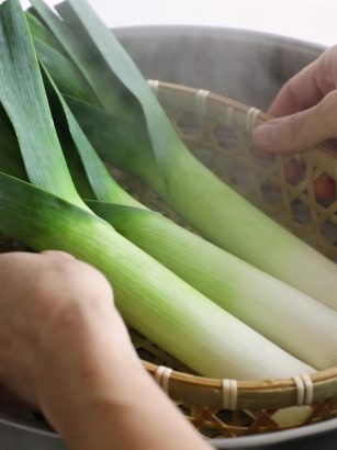 Mains ajustant panier de poireaux verts dans cuit vapeur