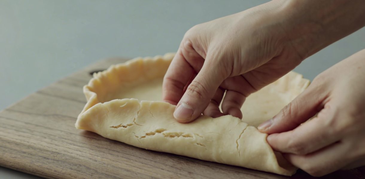 mains étalent une pate brisee huilee sur planche