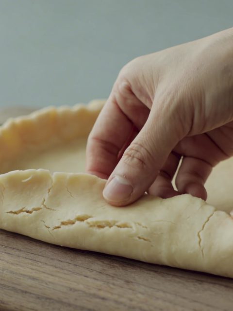 mains étalent une pate brisee huilee sur planche