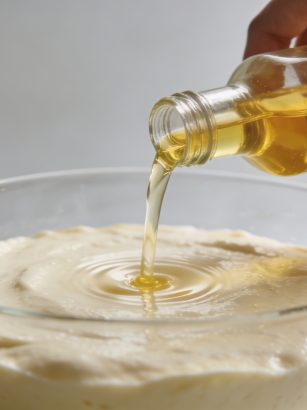 Mains versant huile vegetale dans pate a gateau