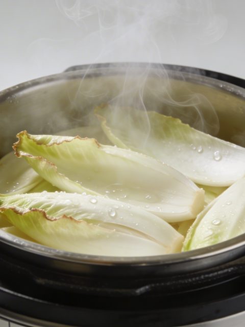 Marmite autocuiseur fumante avec endives tranchees dedans