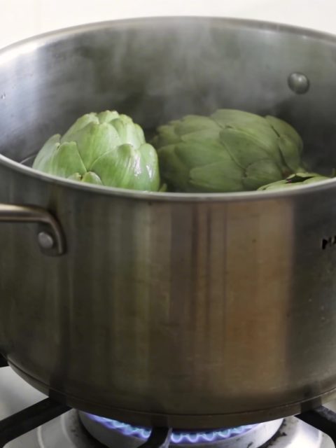 Marmite haute sur gaz avec artichauts verts vapeur