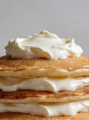 Pile de pancakes dores nappes de fromage blanc