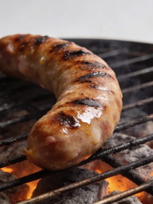 Saucisse de Morteau grillant sur barbecue au charbon