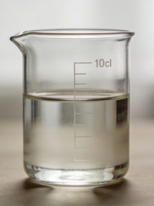 Verre doseur transparent rempli a 10 cl sur table